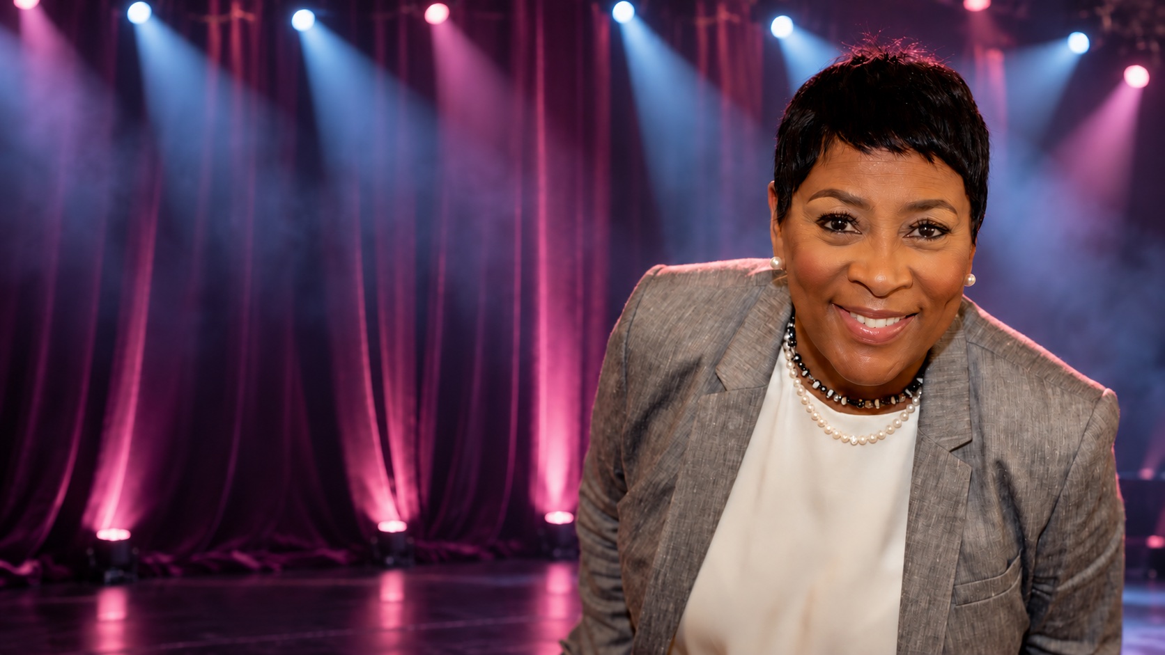 Ms. Vickie with plum theater curtains and cinematic stage lighting
